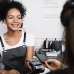 jak płacić telefonem - kobieta płacąca telefonem w sklepie